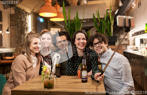 Image of friends taking selfie by smartphone at bar or cafe