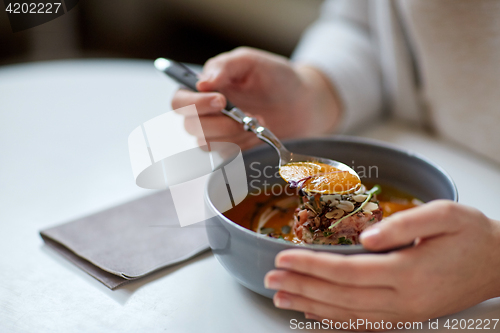 Image of woman eating pumpkin cream soup at restaurant