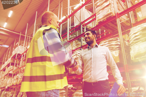 Image of worker and businessmen with clipboard at warehouse