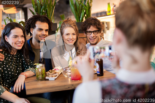 Image of friends with smartphone photographing at cafe