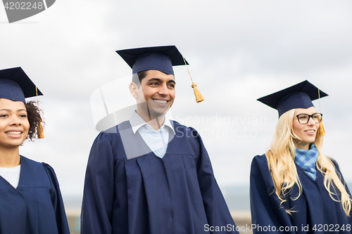 Image of happy students or bachelors in mortar boards