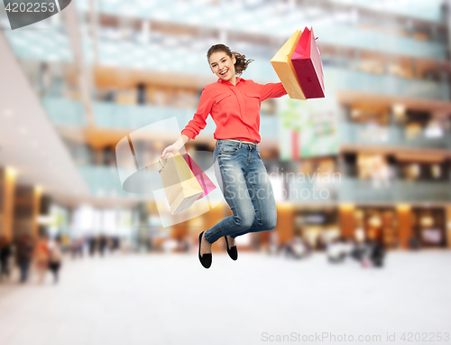 Image of smiling young woman with shopping bags jumping