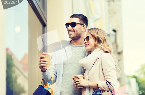 Image of happy couple with shopping bags and coffee in city