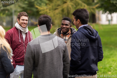 Image of happy friends walking along autumn park