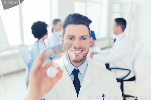 Image of happy doctor over group of medics at hospital