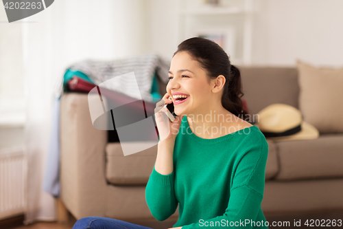 Image of happy woman calling on smartphone at home