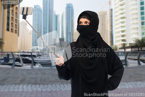 Image of muslim woman in hijab taking selfie by smartphone