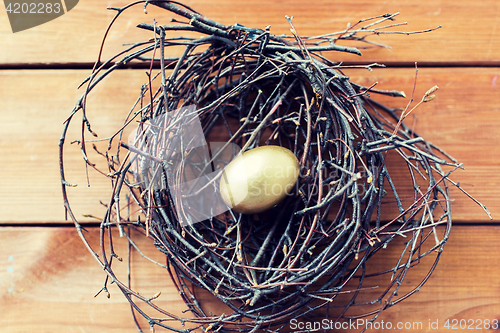 Image of close up of golden easter egg in nest on wood