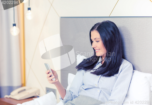 Image of happy businesswoman with smartphone in hotel room