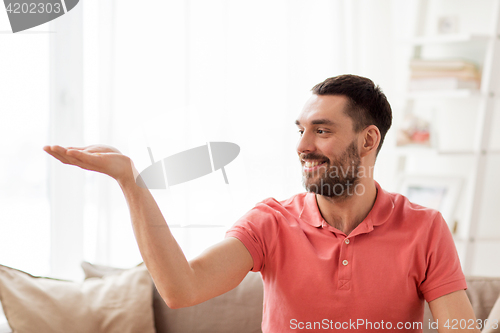 Image of happy man holding something imaginary at home