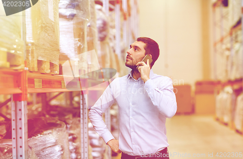 Image of serious man calling on smartphone at warehouse