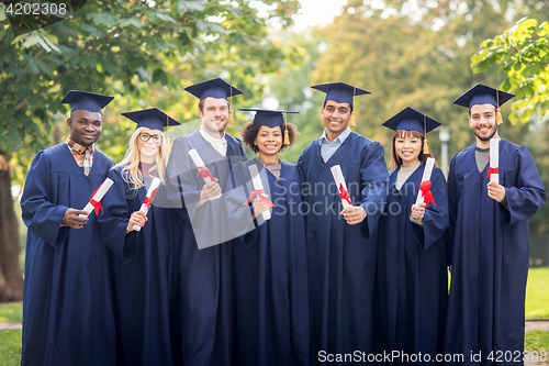 Image of happy students in mortar boards with diplomas