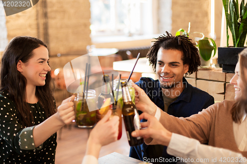 Image of happy friends clinking drinks at bar or cafe