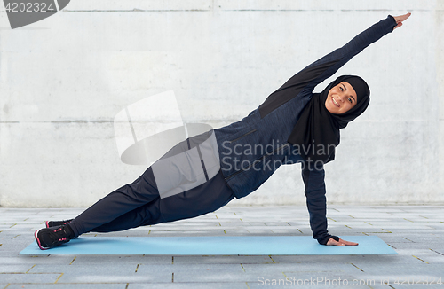 Image of muslim woman doing sport on mat