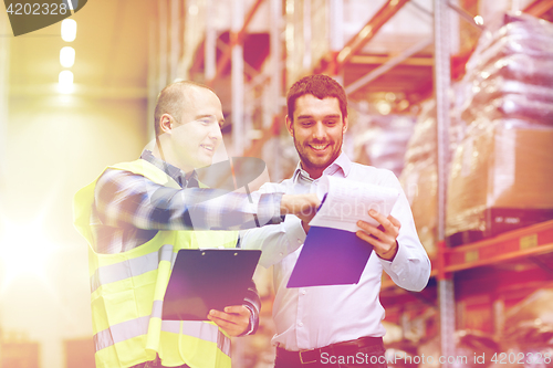 Image of worker and businessmen with clipboard at warehouse