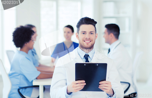 Image of happy doctor with tablet pc over team at clinic