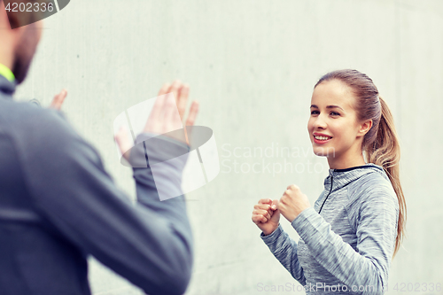 Image of happy woman with coach working out strike outdoors