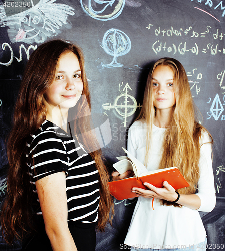 Image of back to school after summer vacations, two teen real girls in classroom with blackboard painted together, lifestyle people concept