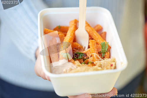 Image of close up of hand holding plate with sweet potato