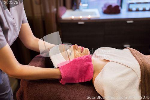 Image of woman having face massage with terry gloves at spa