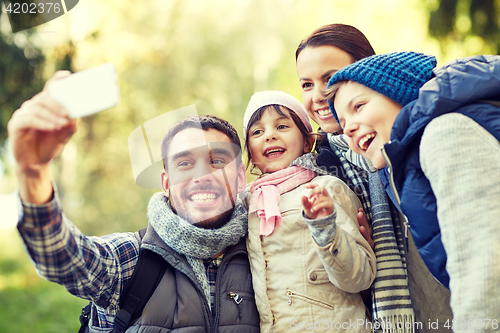 Image of family taking selfie with smartphone outdoors