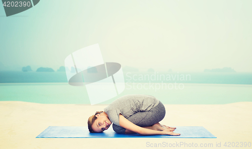 Image of happy woman making yoga in child pose on mat