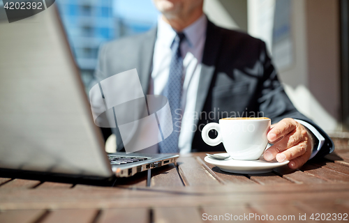 Image of senior businessman with laptop and coffee outdoors