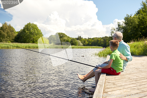 Image of grandfather and grandson fishing on river berth