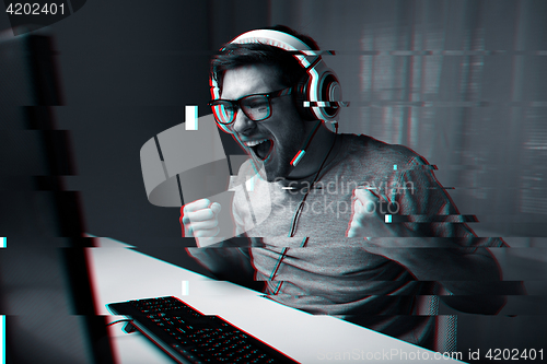 Image of man in headset playing computer video game at home