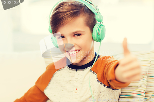 Image of happy boy in headphones showing thumbs up at home