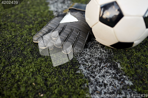 Image of soccer ball and goalkeeper gloves on field