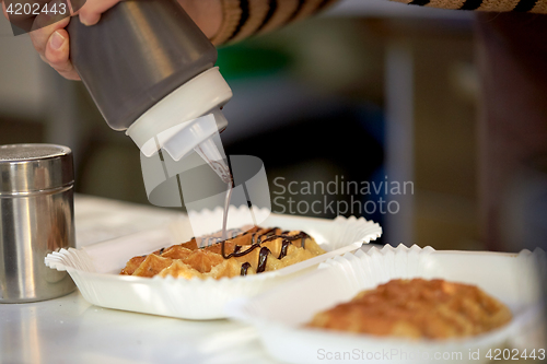 Image of close up of cook adding syrop to waffle