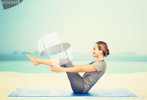 Image of woman making yoga in half-boat pose on mat