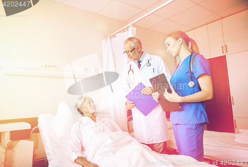 Image of doctor and nurse visiting senior woman at hospital