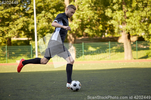 Image of soccer player playing with ball on football field