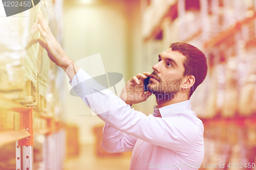 Image of serious man calling on smartphone at warehouse