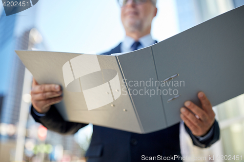 Image of senior businessman with ring binder folder in city