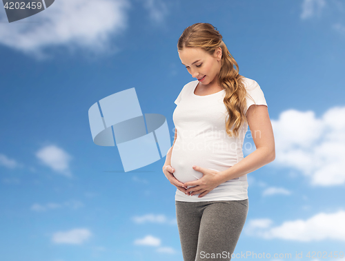 Image of happy pregnant woman touching her big belly