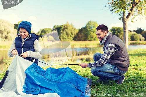 Image of happy father and son setting up tent outdoors