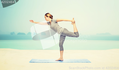 Image of woman making yoga in lord of the dance pose on mat