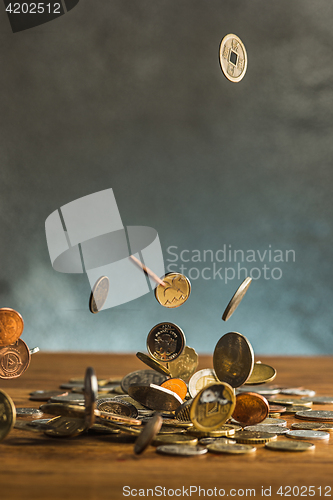 Image of The silver and golden coins and falling coins on wooden background