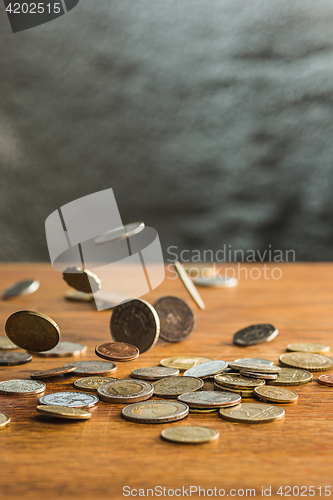 Image of The silver and golden coins and falling coins on wooden background