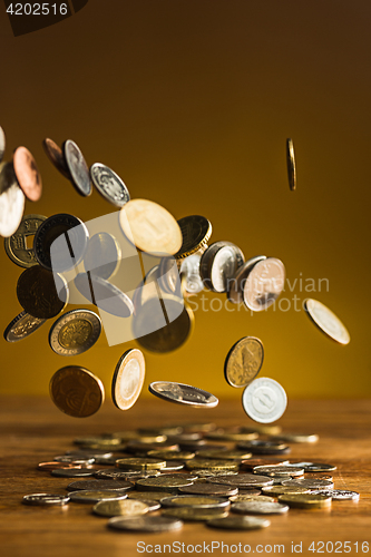 Image of The silver and golden coins and falling coins on wooden background