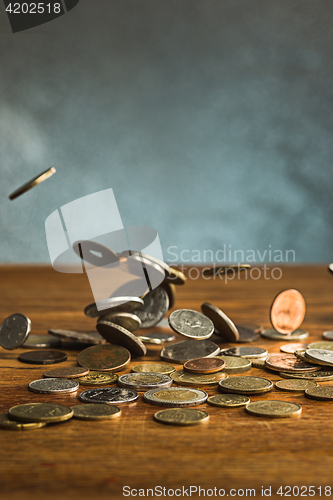 Image of The silver and golden coins and falling coins on wooden background