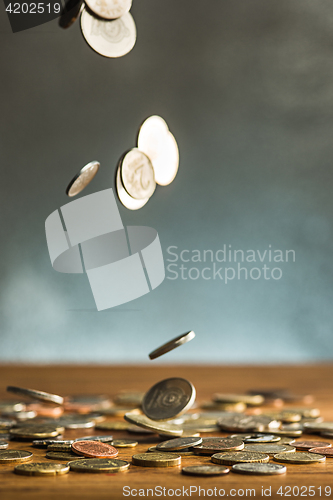 Image of The silver and golden coins and falling coins on wooden background