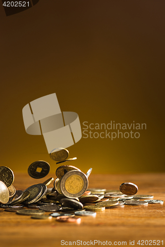 Image of The silver and golden coins and falling coins on wooden background