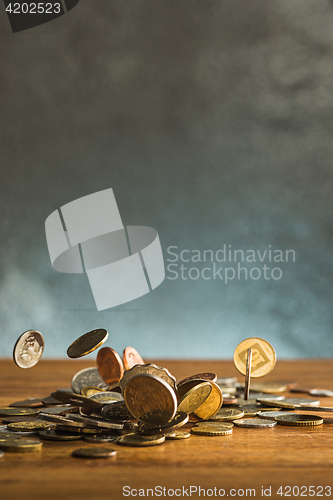 Image of The silver and golden coins and falling coins on wooden background