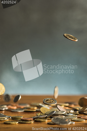 Image of The silver and golden coins and falling coins on wooden background