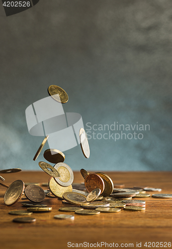 Image of The silver and golden coins and falling coins on wooden background