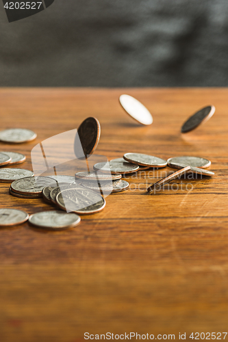 Image of The silver and golden coins and falling coins on wooden background